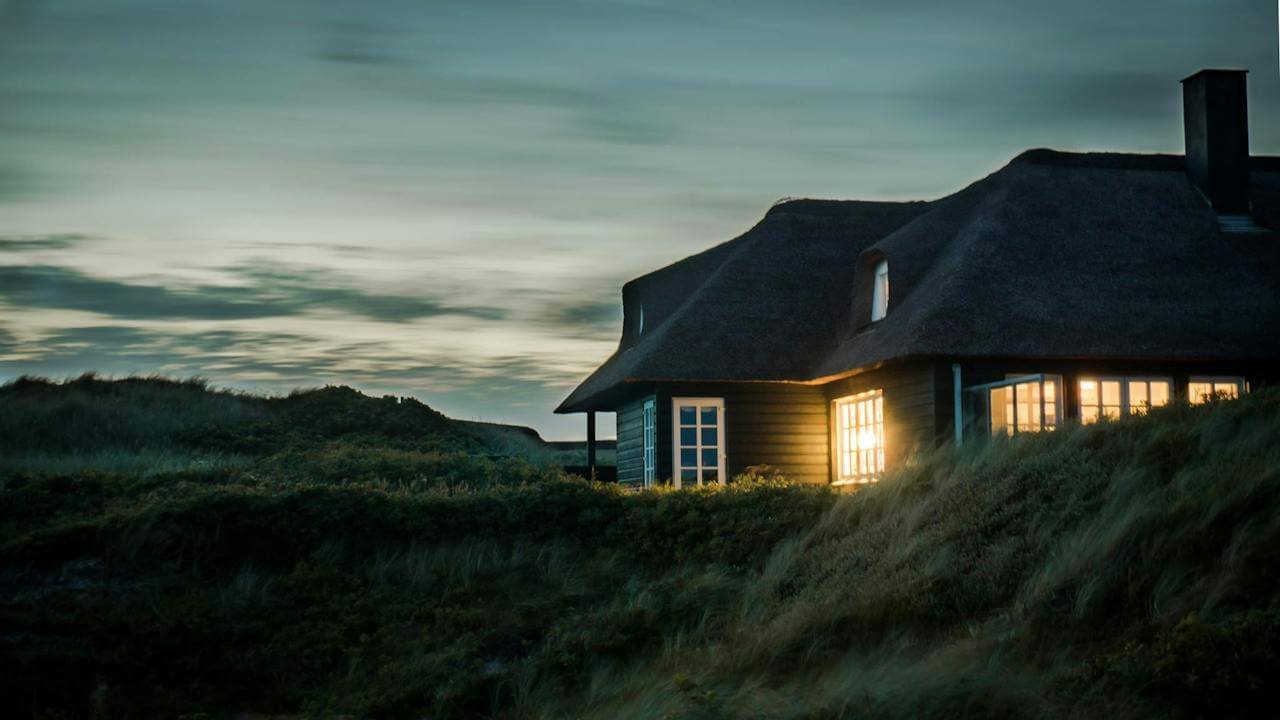 A wooden house on a green hill, evening time.